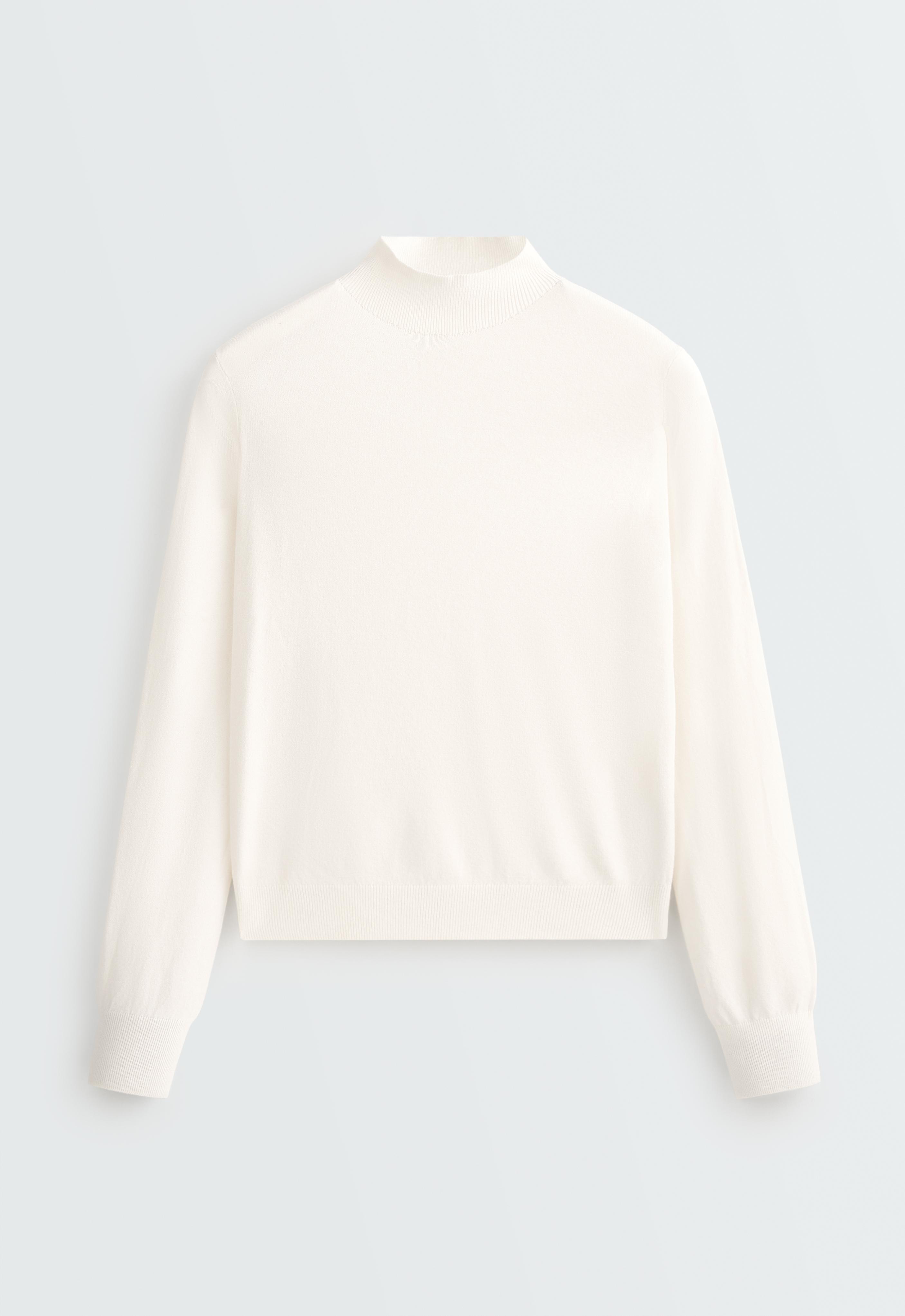 Front view of a light ecru sweater with a turtleneck, long sleeves, and ribbed cuffs and hem. — photo 1 of 1