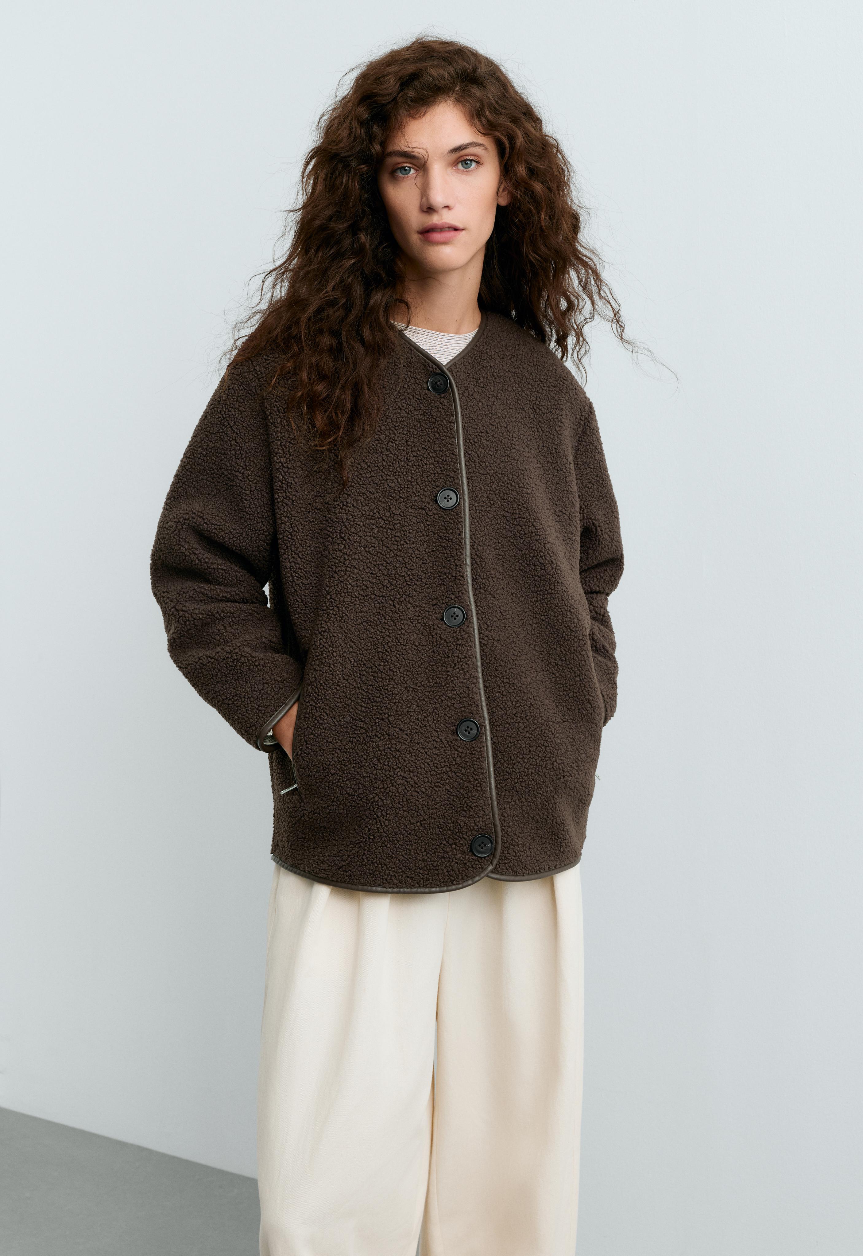 Dark brown jacket set with a round neckline, front buttons, and side pockets, cream wide-leg pants, and a striped T-shirt.