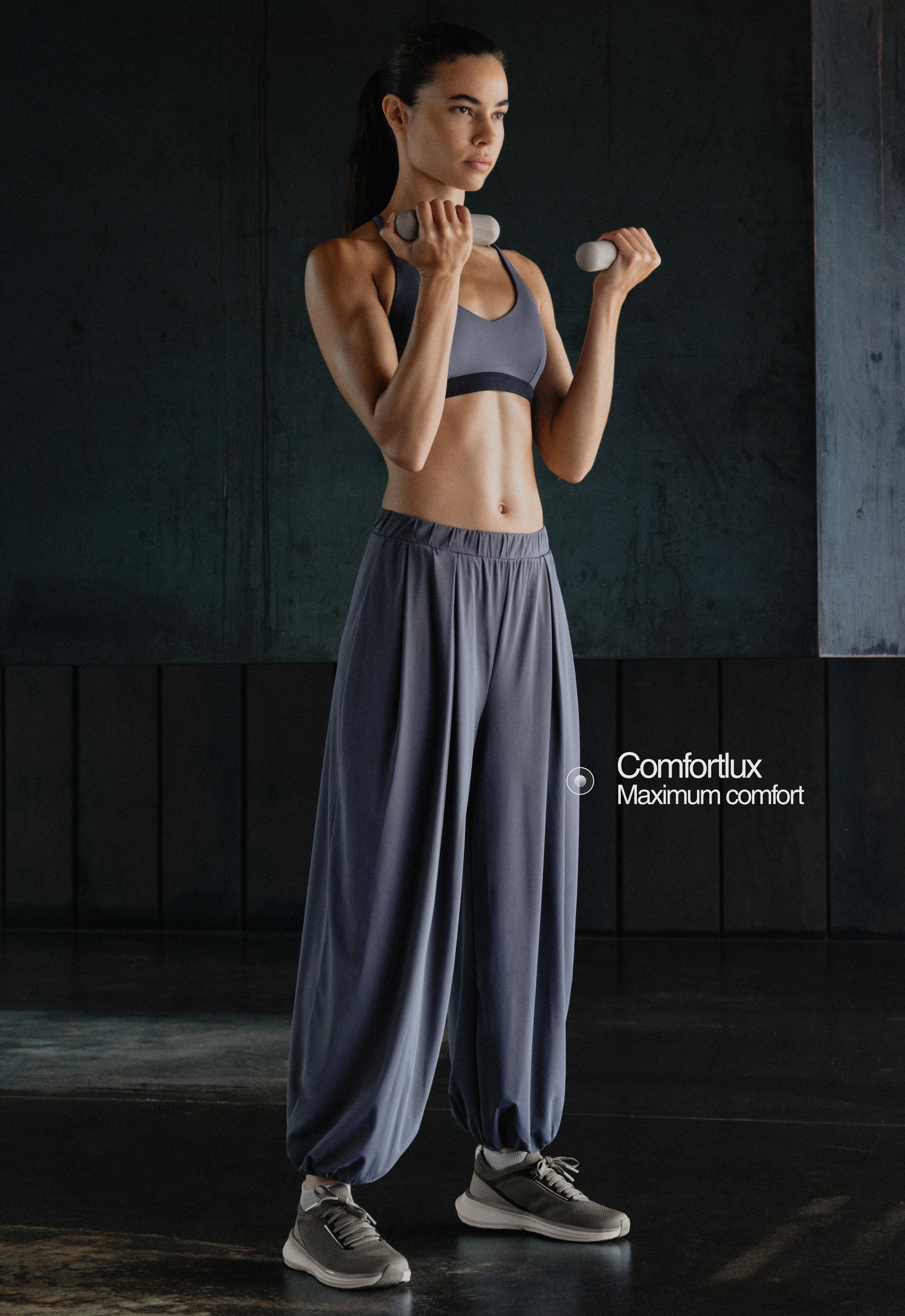Set consisting of a sports bra and blue-gray jogger pants with an elastic high waist, front pleats, and tapered cuffs.