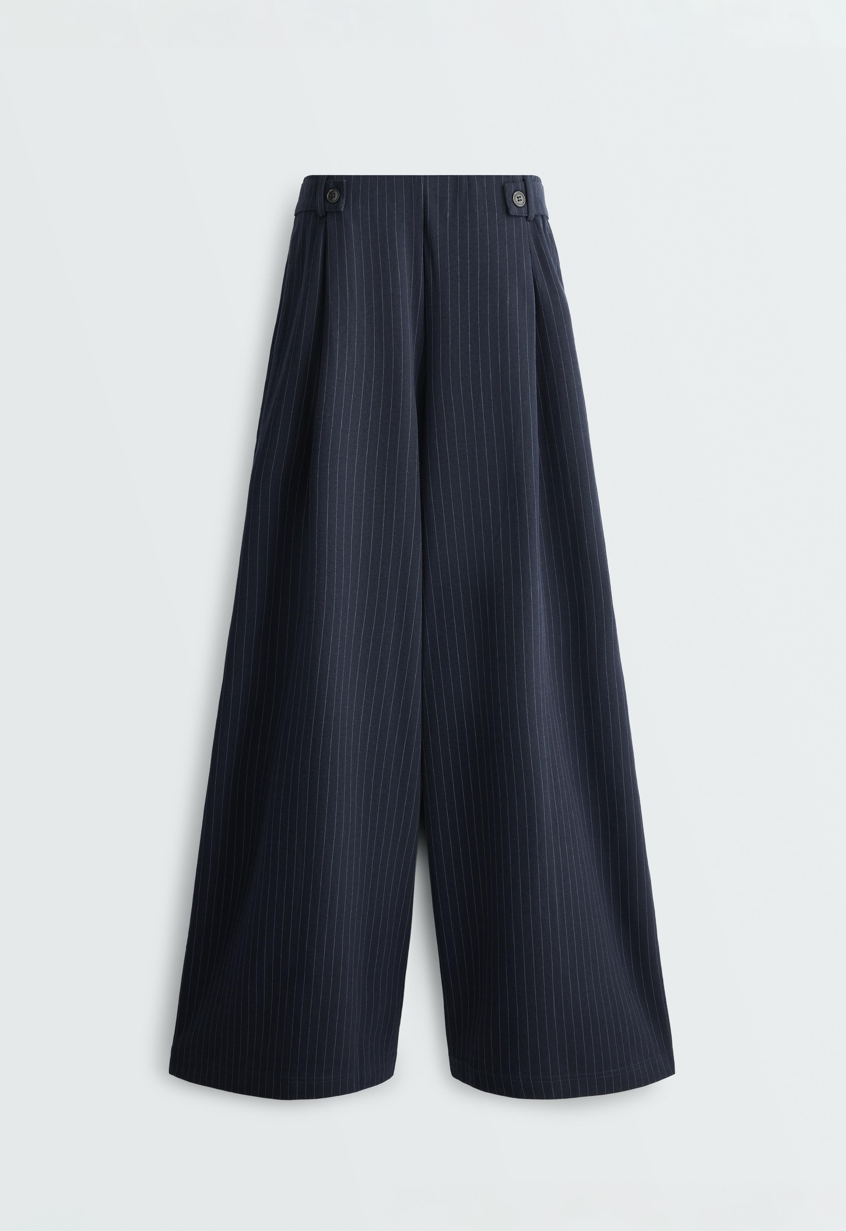 Front view of wide-leg navy blue pants with pinstripes, front pleats, and buttons on the sides of the waistband.