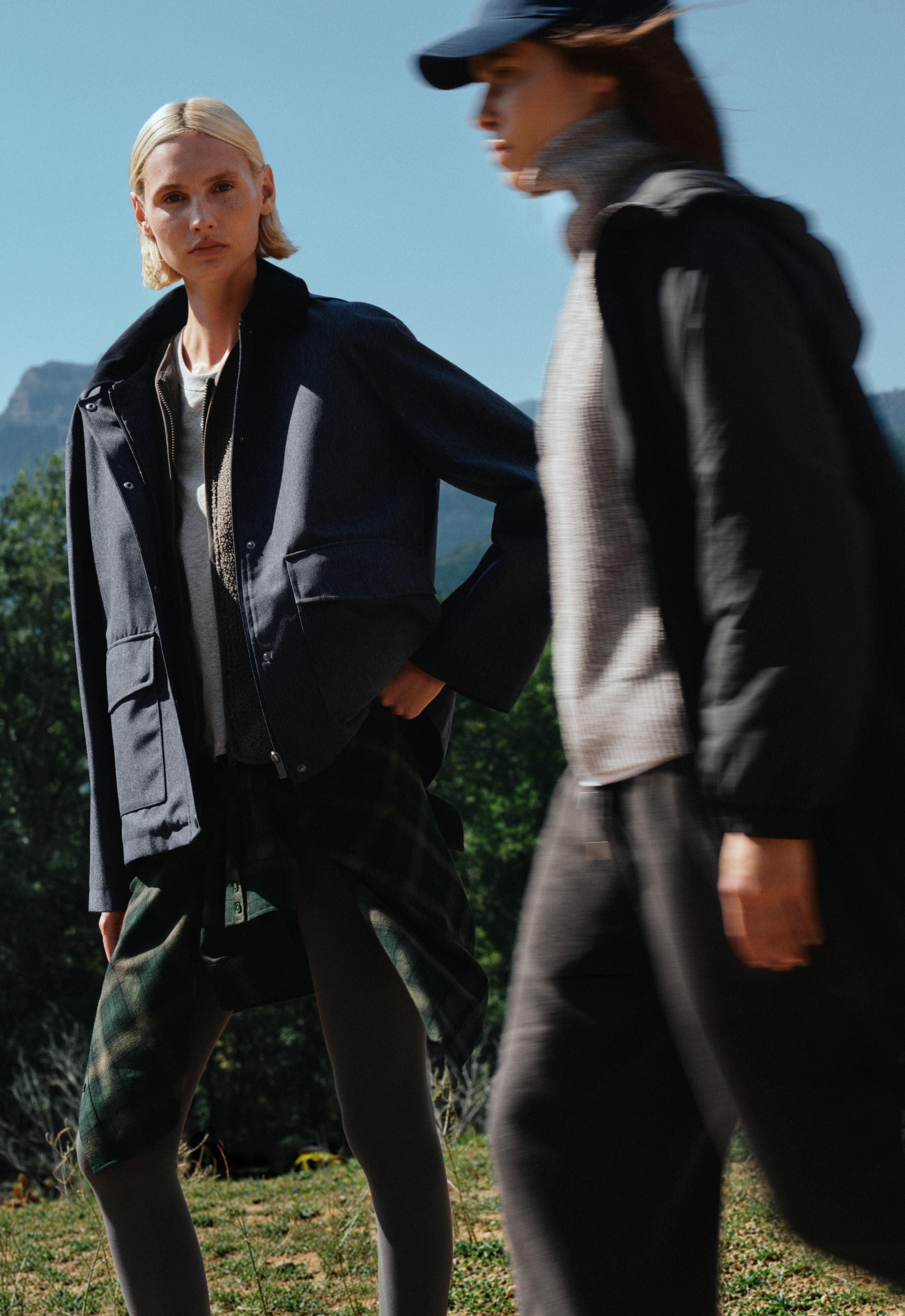 Charcoal jacket set with front pockets, gray top, plaid shirt tied around the waist, and dark leggings.