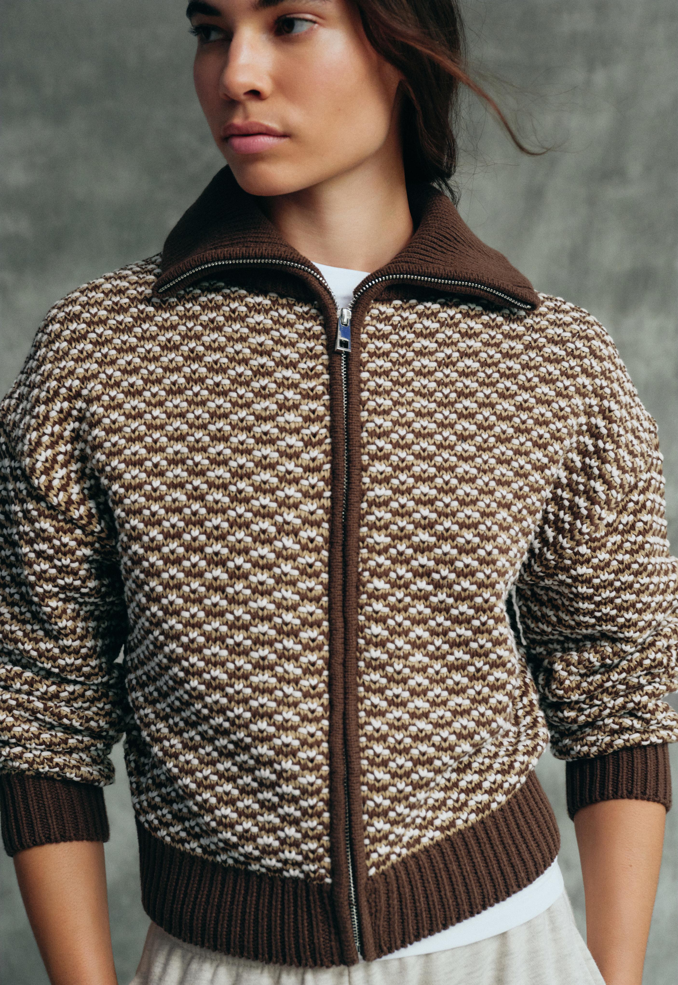 Medium shot of a jacket with a geometric pattern, front zipper closure, and a ribbed collar, cuffs, and hem in cocoa.