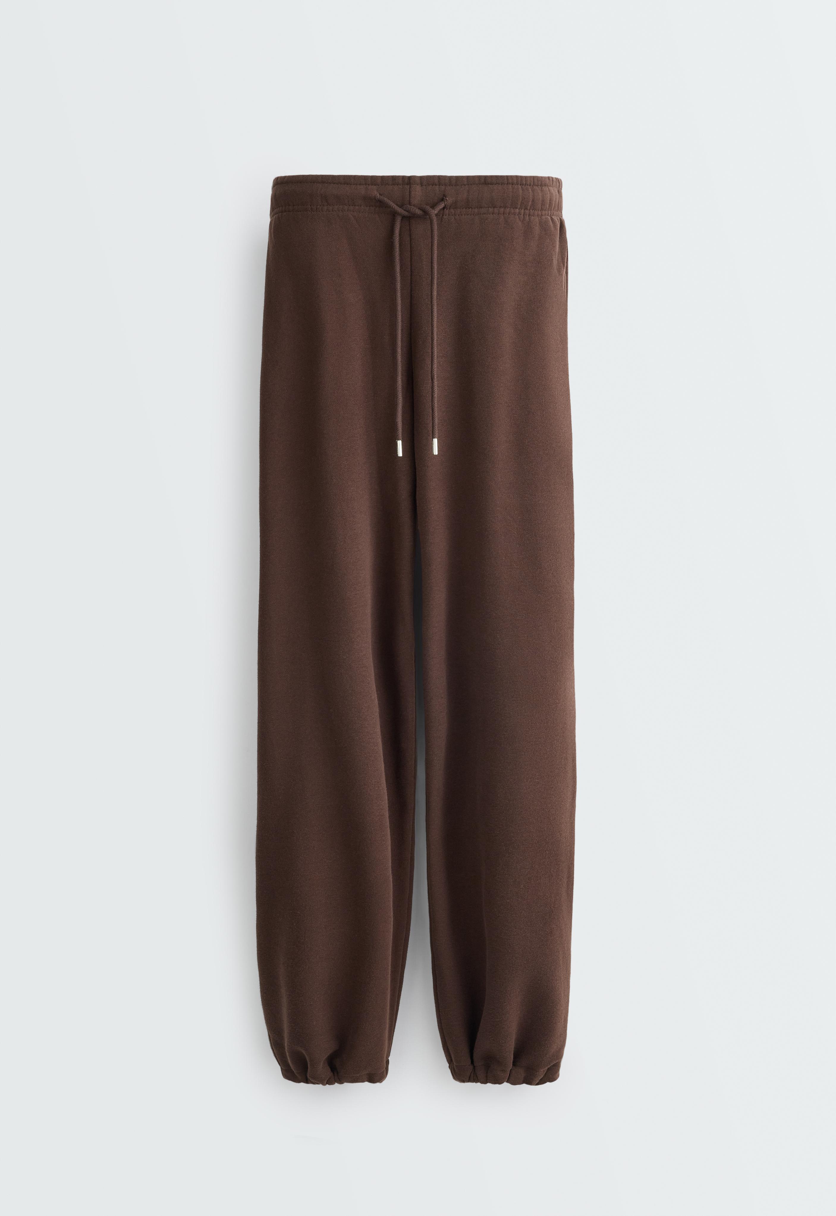 Front view of dark reddish-brown pants with an elastic waistband, adjustable drawstring, and elastic cuffs.