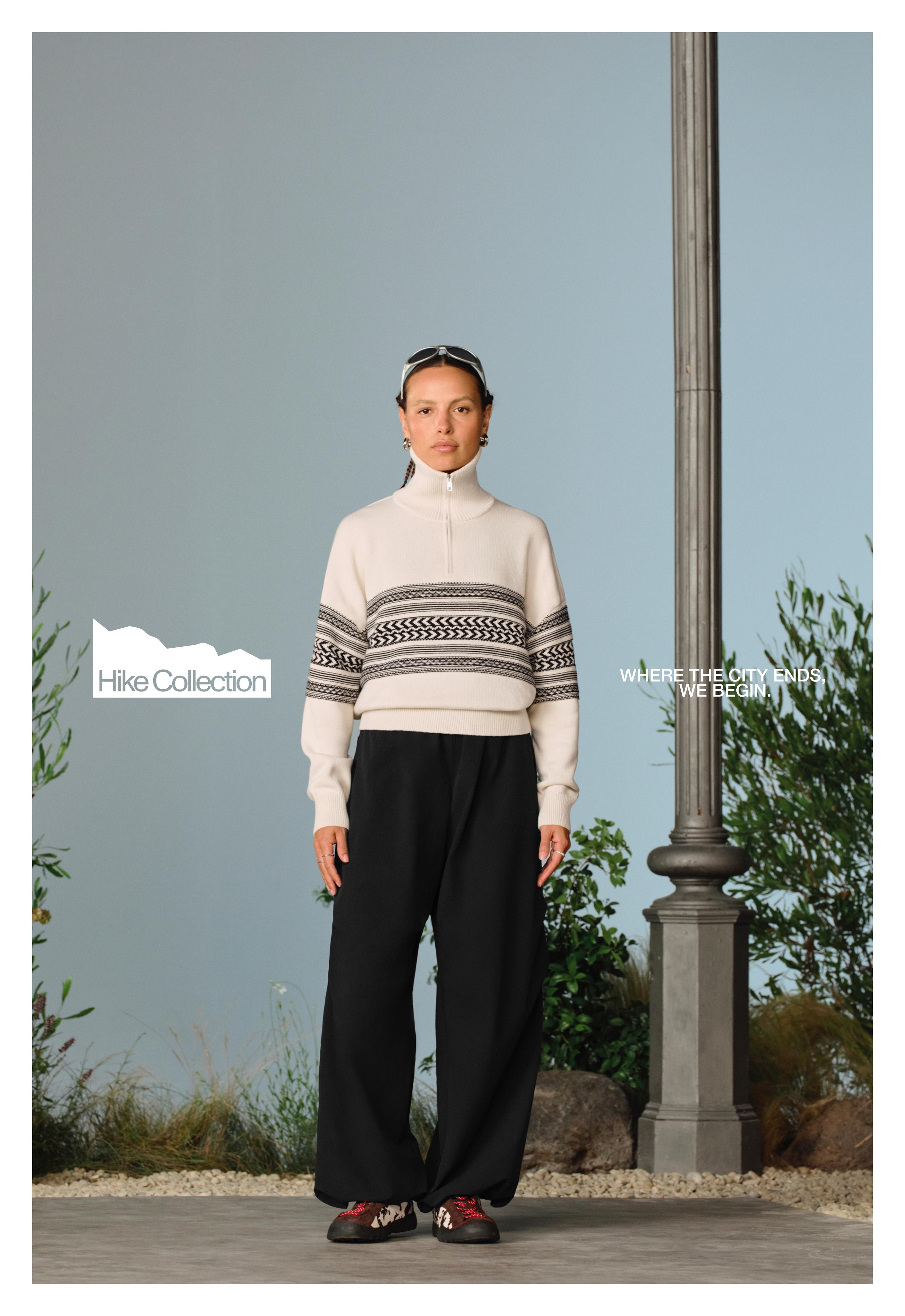 mock-neck jersey set with a half-zip and contrasting jacquard stripe, wide-leg black pants, and sneakers.