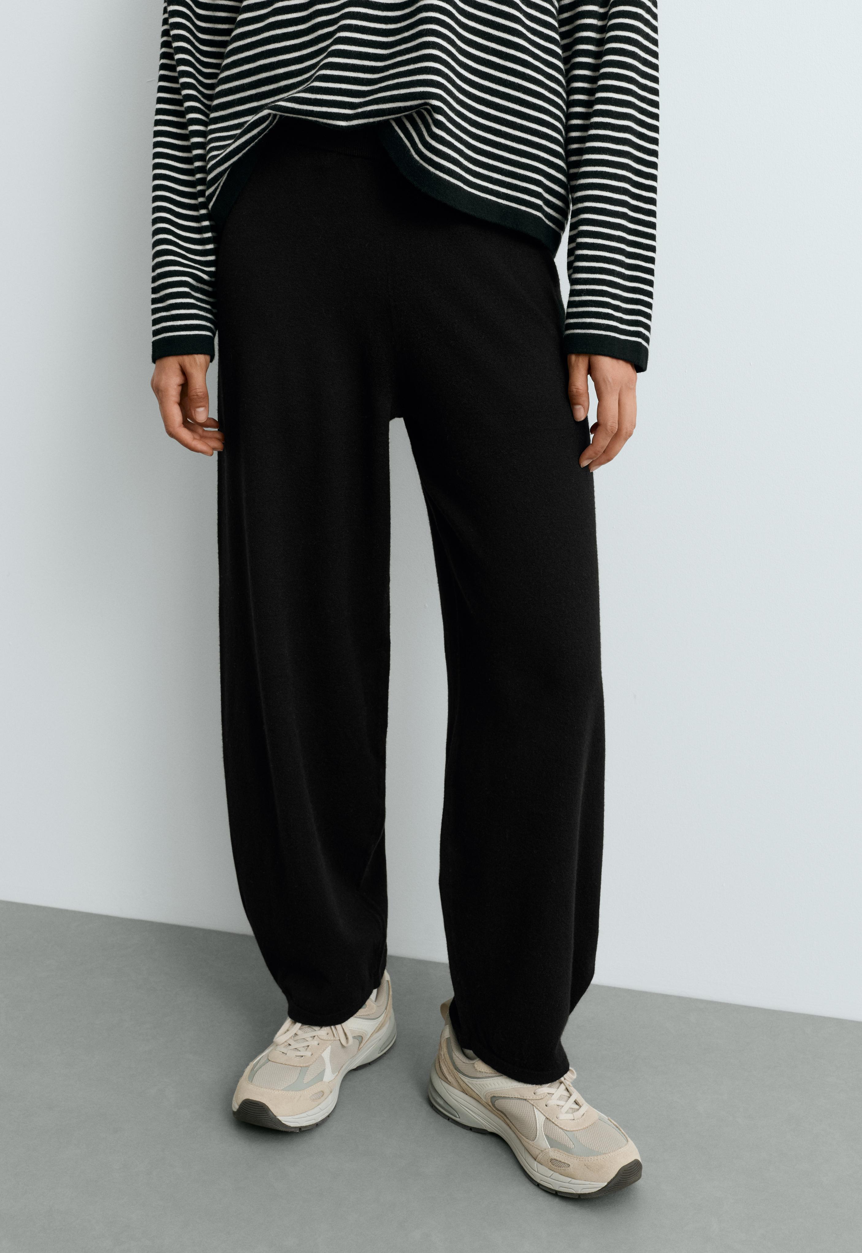 Striped T-shirt, black balloon-fit pants with pleats at the hem, and sneakers.
