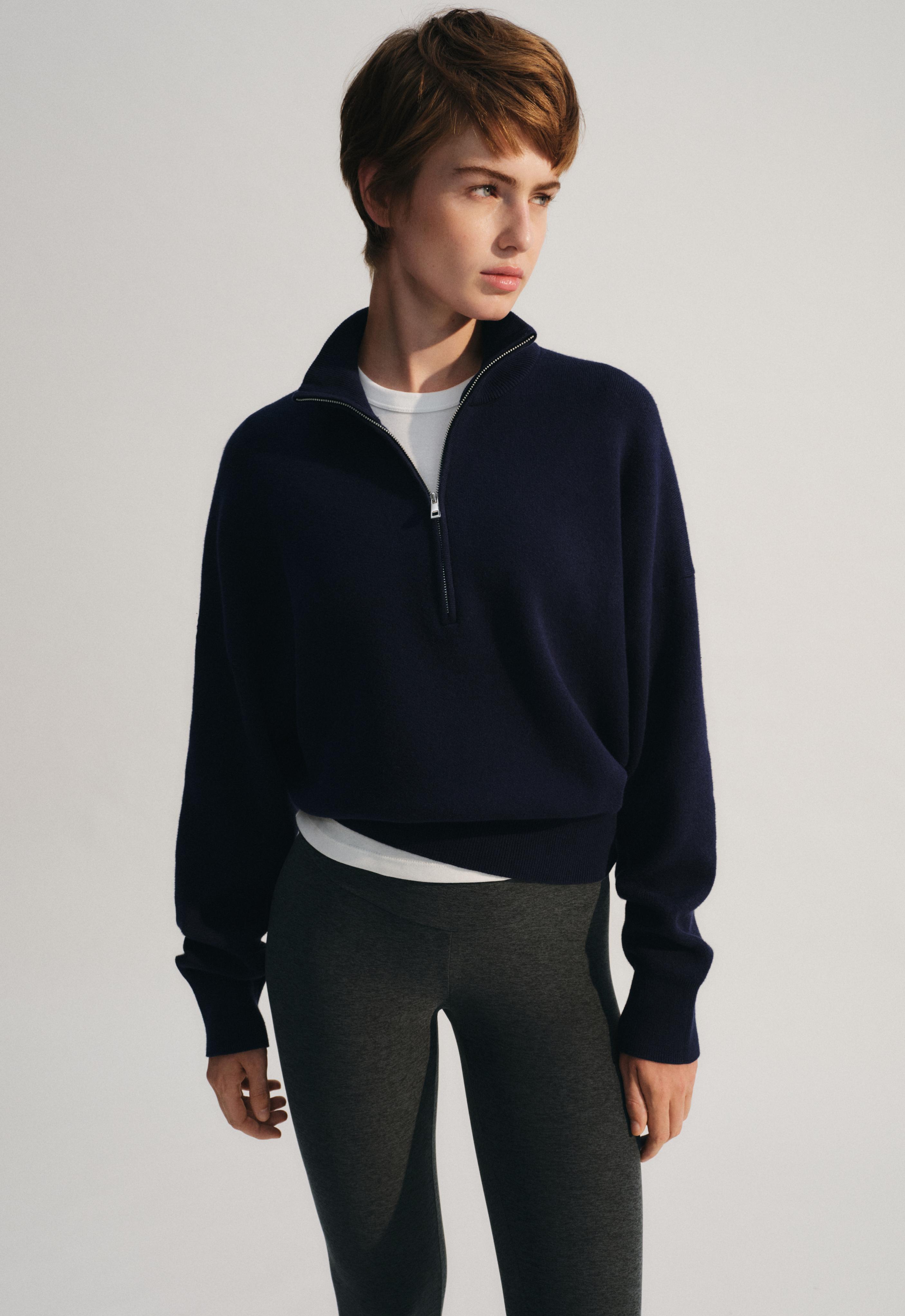 Navy blue long-sleeved turtleneck half-zip sweater set with a white t-shirt and dark gray leggings.