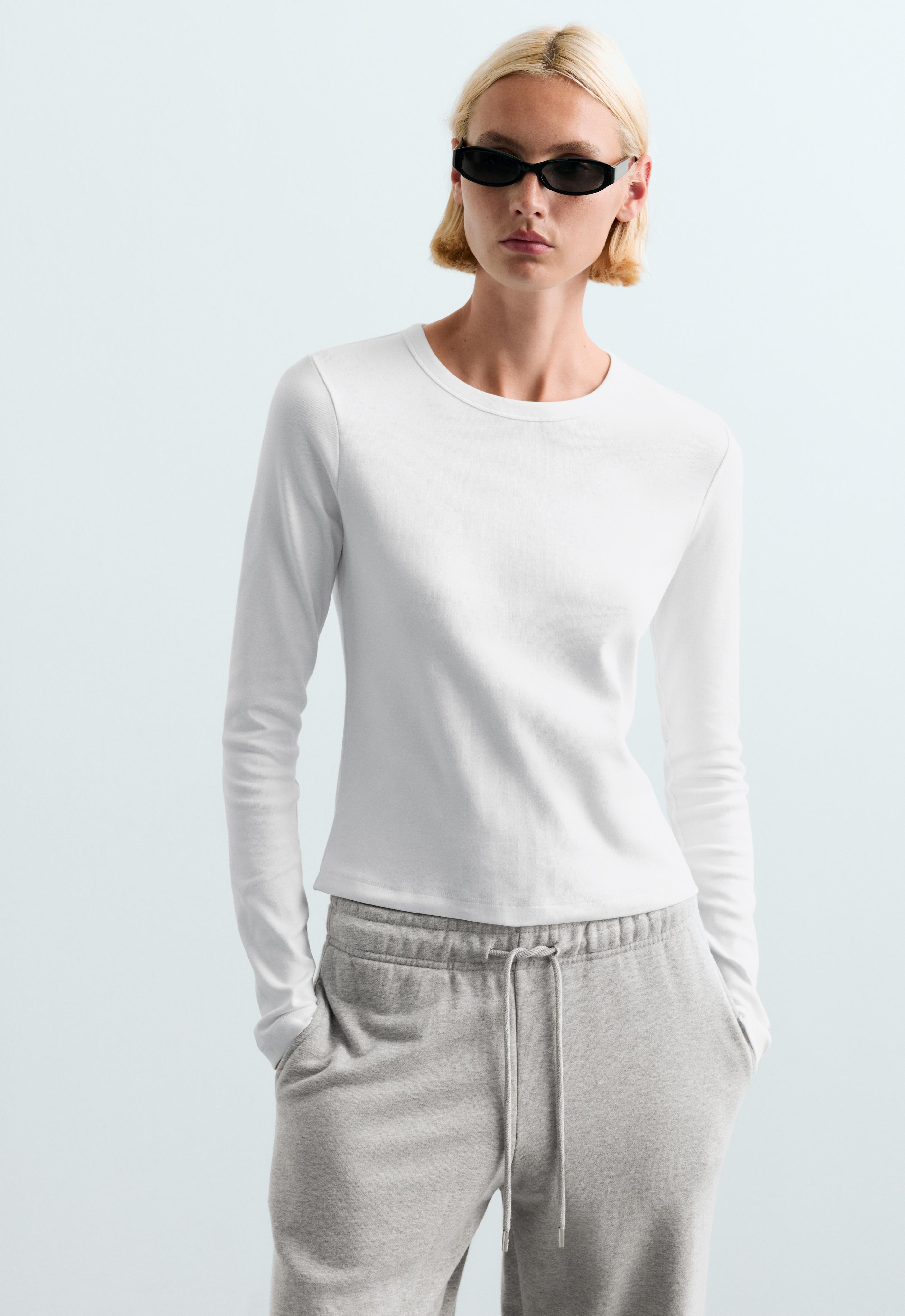 Set consisting of a white long-sleeve crew-neck shirt and gray pants with an adjustable drawstring and side pockets.