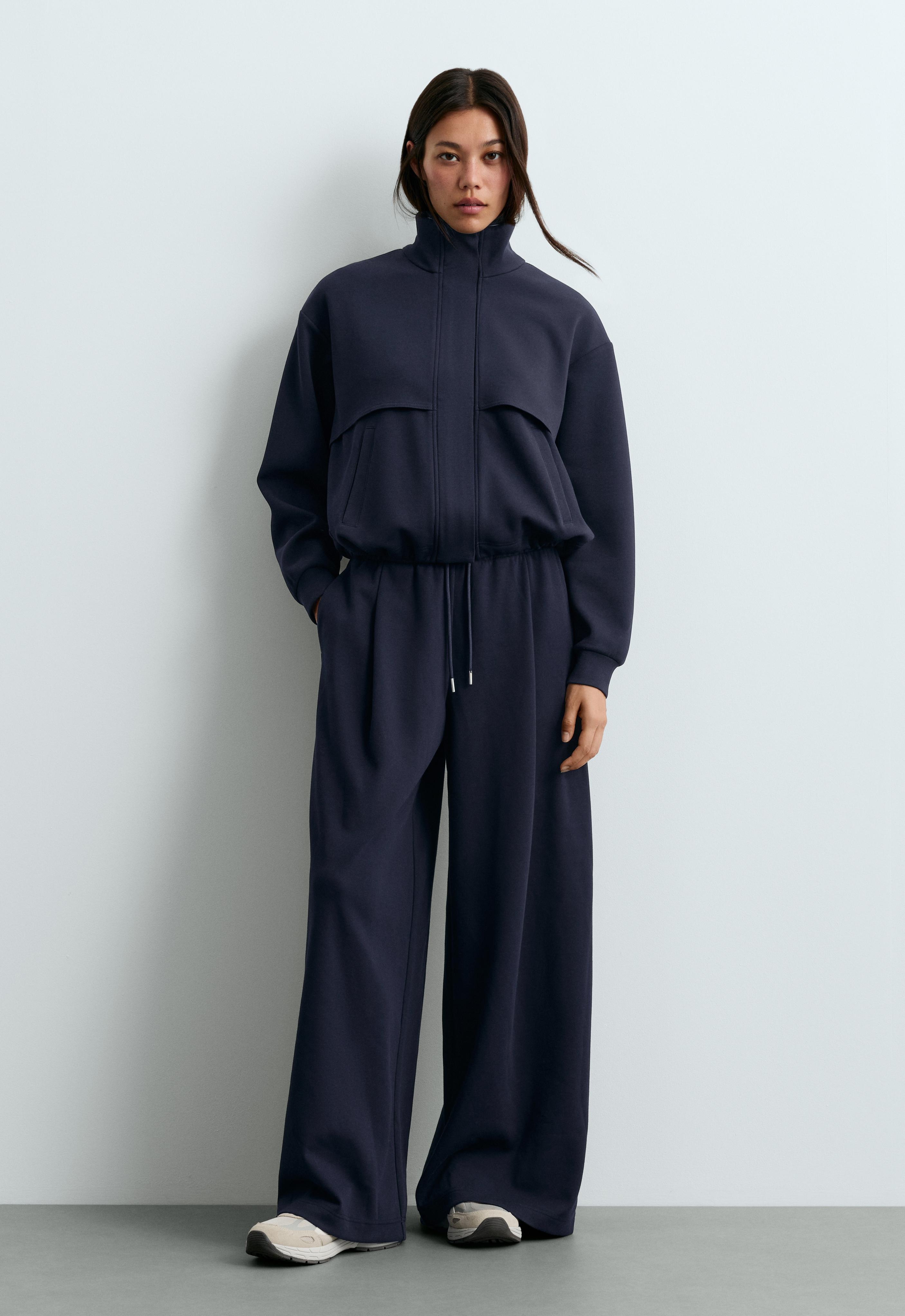 Set consisting of a blue-dyed jacket with a high collar, cape detail, and front pockets, and wide-leg pants with a drawstring waist.