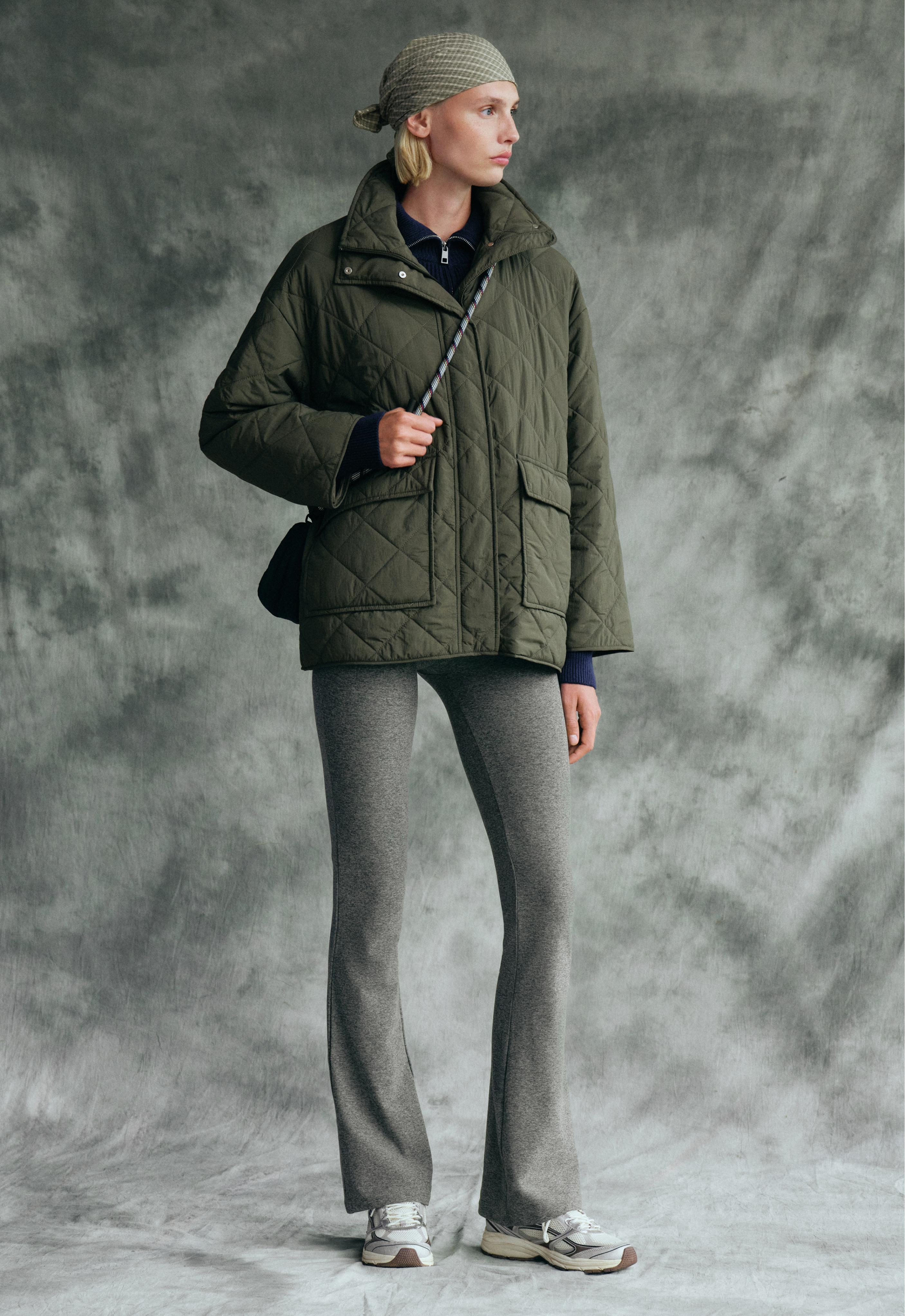 Set consisting of a green quilted jacket with front pockets and high-waisted heather gray flare pants.