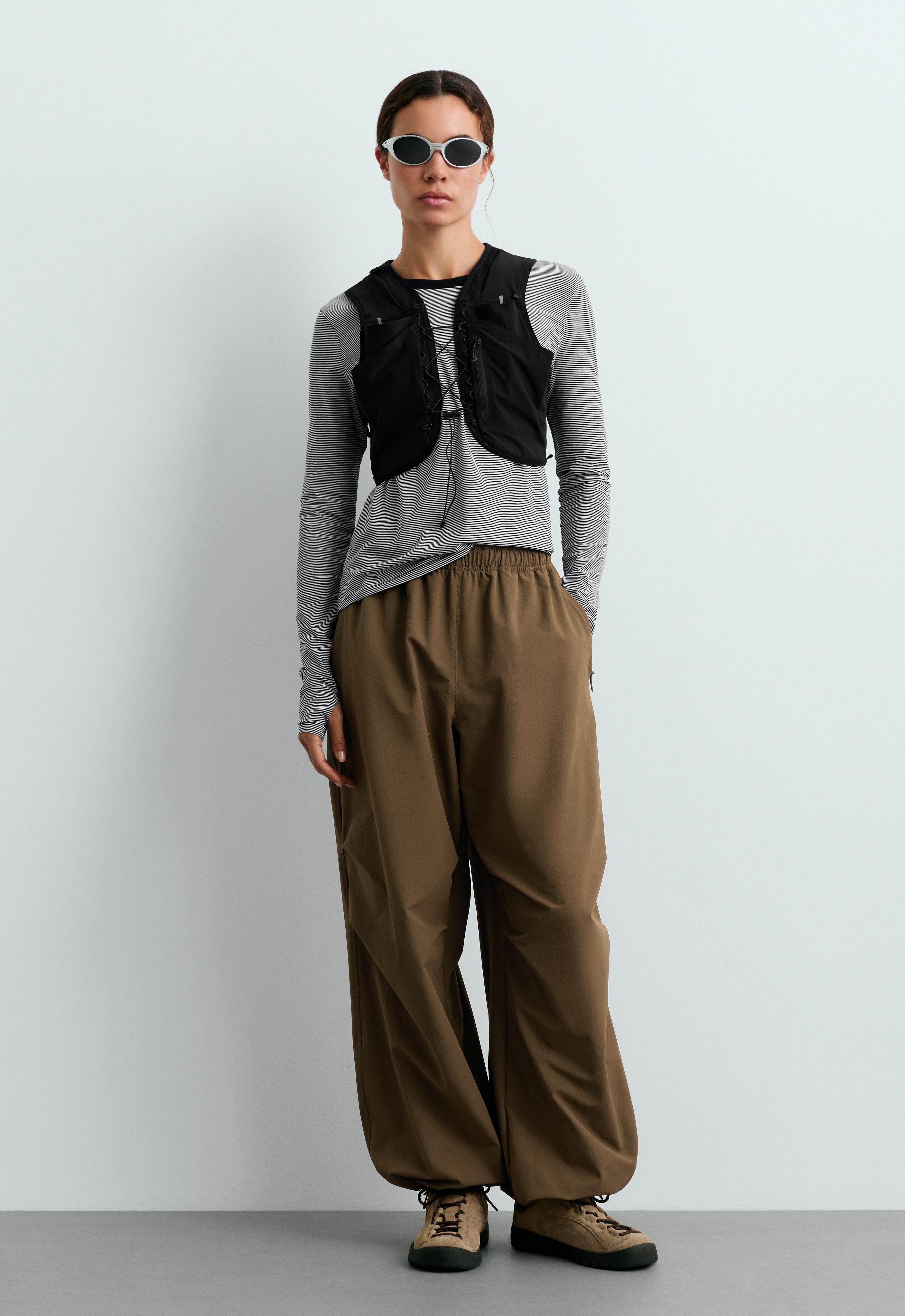 Long-sleeve striped T-shirt set, cropped black lace-up vest, and brown wide-leg pants with an elastic waistband.